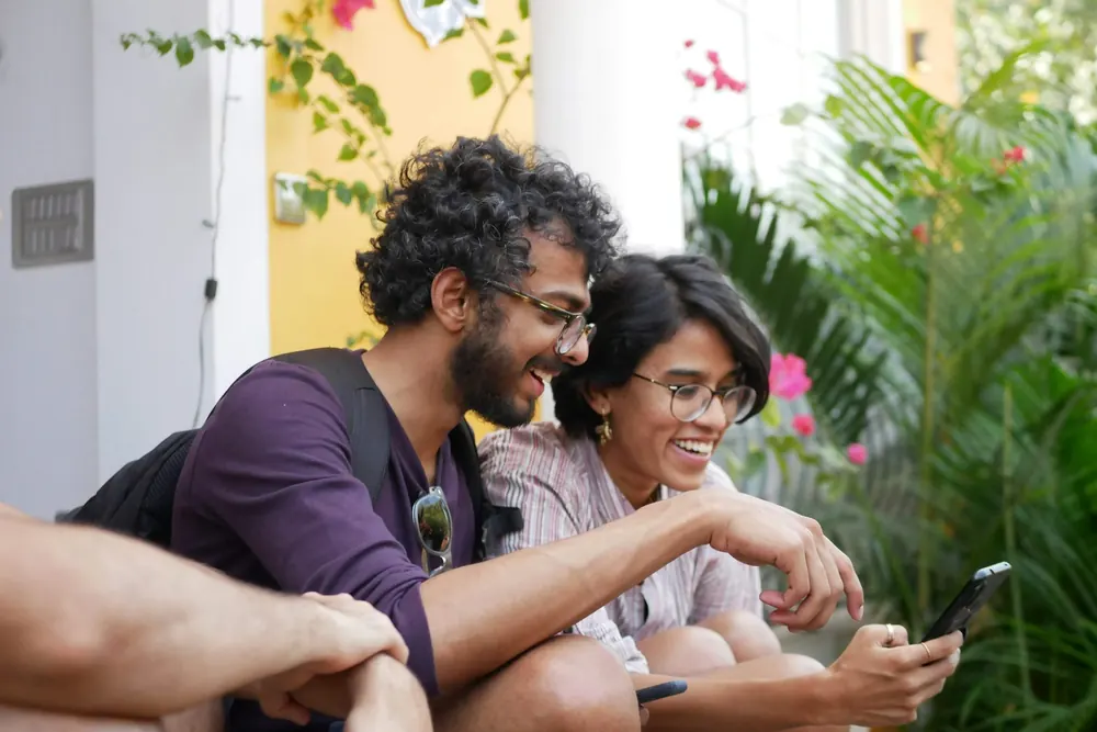 Zwei Freunde lachen gemeinsam über ein Smartphone